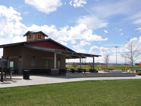 The picnic shelter at Erie Community Park, with ballfield lights behind it and open grass under a wide sky