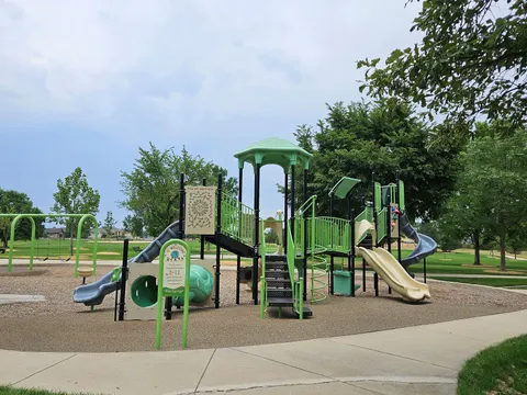 The green playground at Longs Peak Park, with its scavenger-hunt panel, twin slides and swings